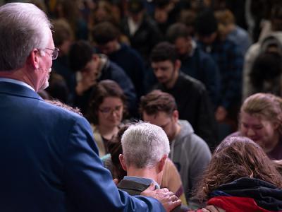 Interim President Dr. Rick Christman places his hands on Dr. Bill Jones as he leads in prayer. (Photo by Noah Allard)